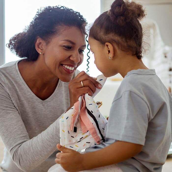 smiling mother wiping daughter's face with a cloth
